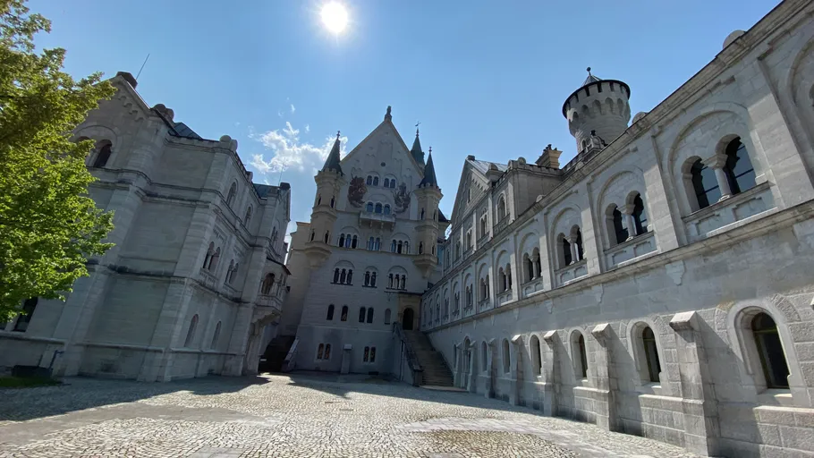 Castle courtyard with towers under sunny sky.