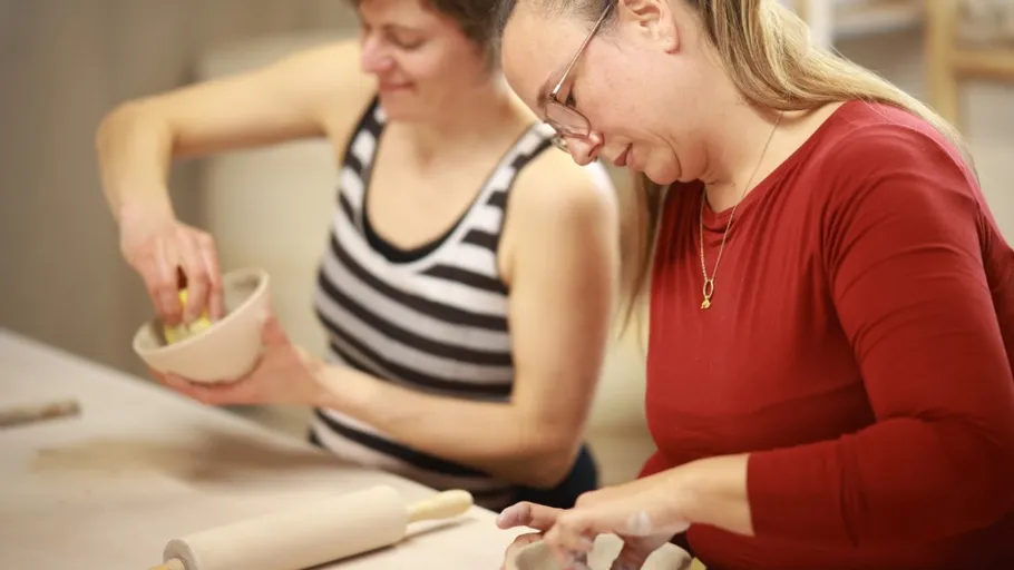 Two women engaged in pottery crafting indoors.