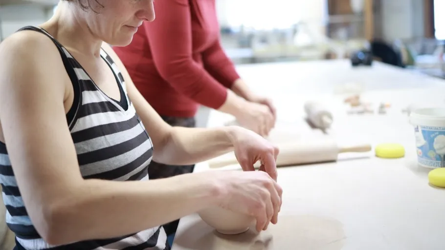 Women shaping pottery in a workshop.