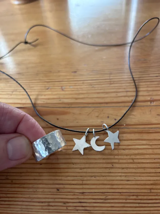 Silver ring, necklace with star and moon charms.