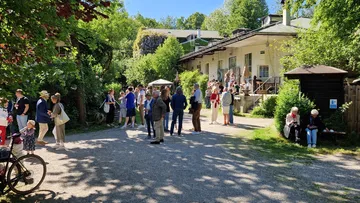Menschen unterhalten sich vor einem Haus, sonniger Tag.