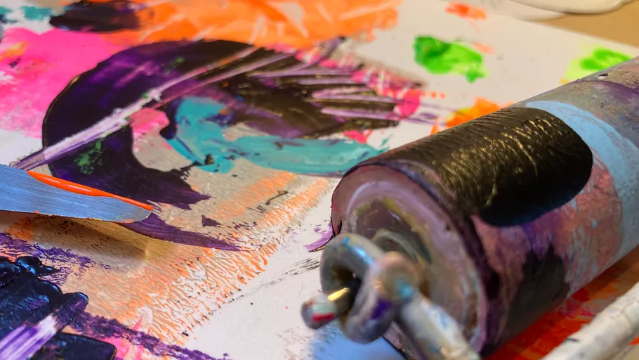 Farbrolle und Messer auf bunter Leinwand.