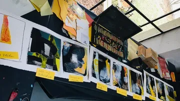 Kunstwerke auf Tisch mit bunten Papieren ausgestellt.