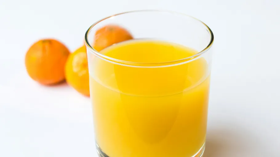 Glas Orangensaft mit Orangen daneben.