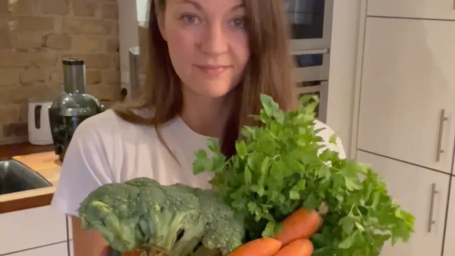 Woman holding vegetables in kitchen.