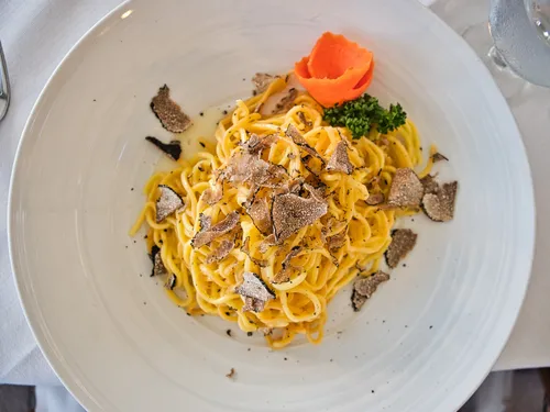 Pasta with truffles and garnish on white plate.