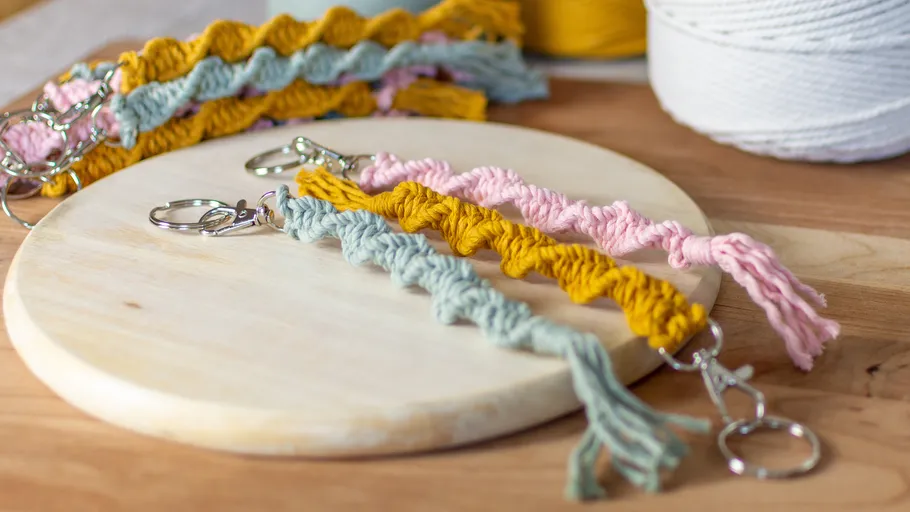 Colored macramé keychains on wooden board.