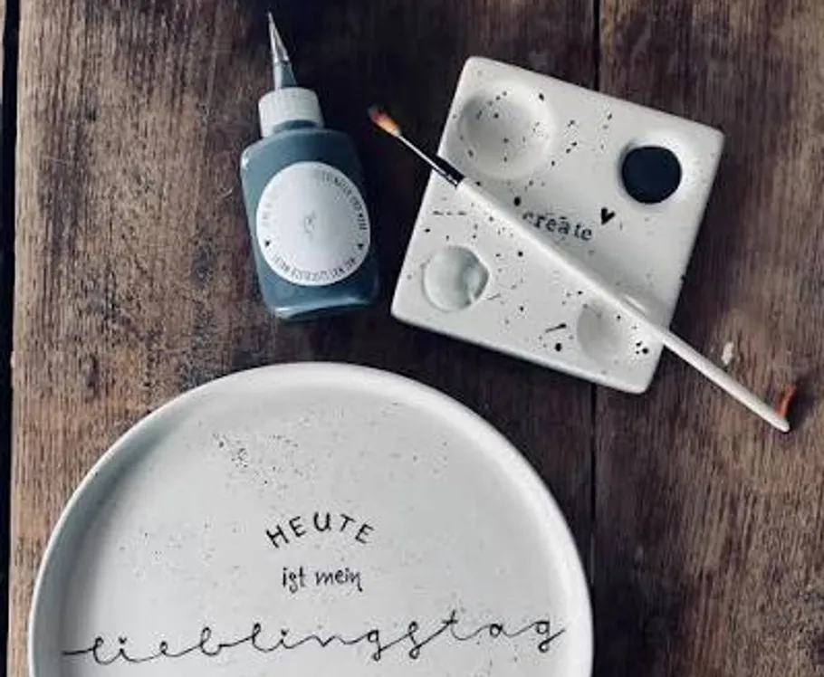 Plate, paint, brush on wooden surface.