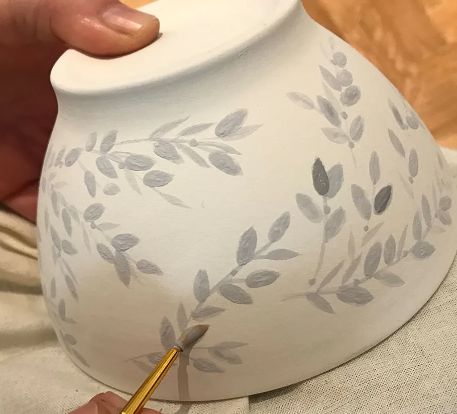 Hand painting floral design on ceramic bowl.