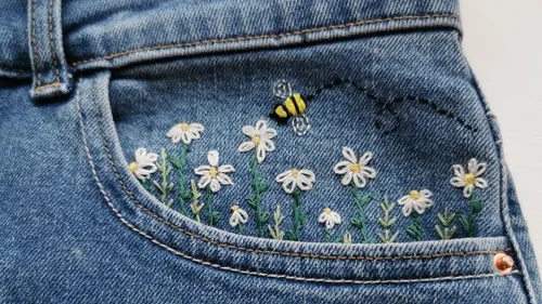 Denim pocket with embroidered flowers and bee.