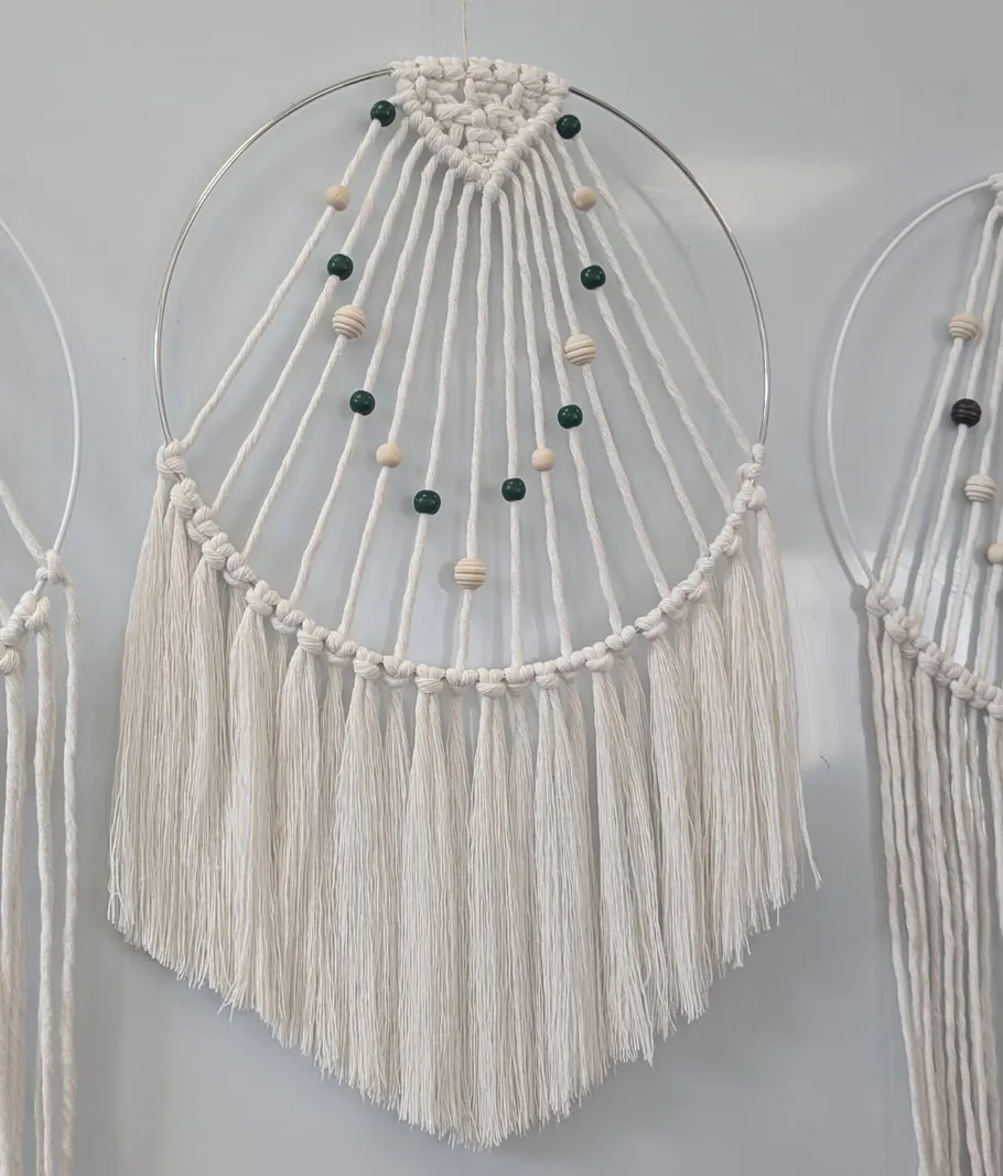Macrame wall hanging with beads, white background.