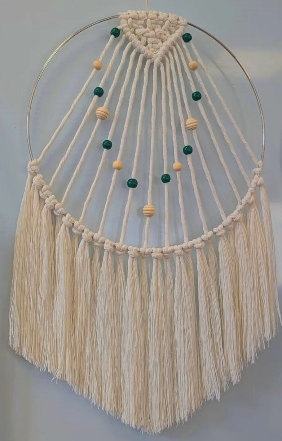 Macramé wall hanging with beads on a wall.