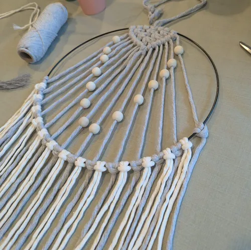 Macramé with beads on a metal hoop.
