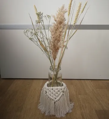 Getrocknete Blumen im Glas mit Makramee-Umschlag.