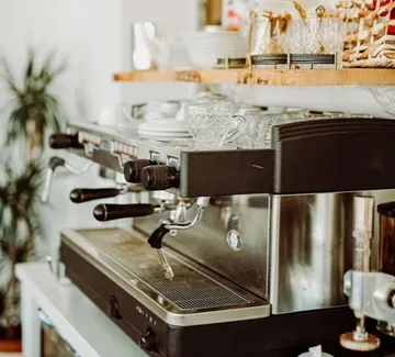 Espresso machine on counter with glassware.