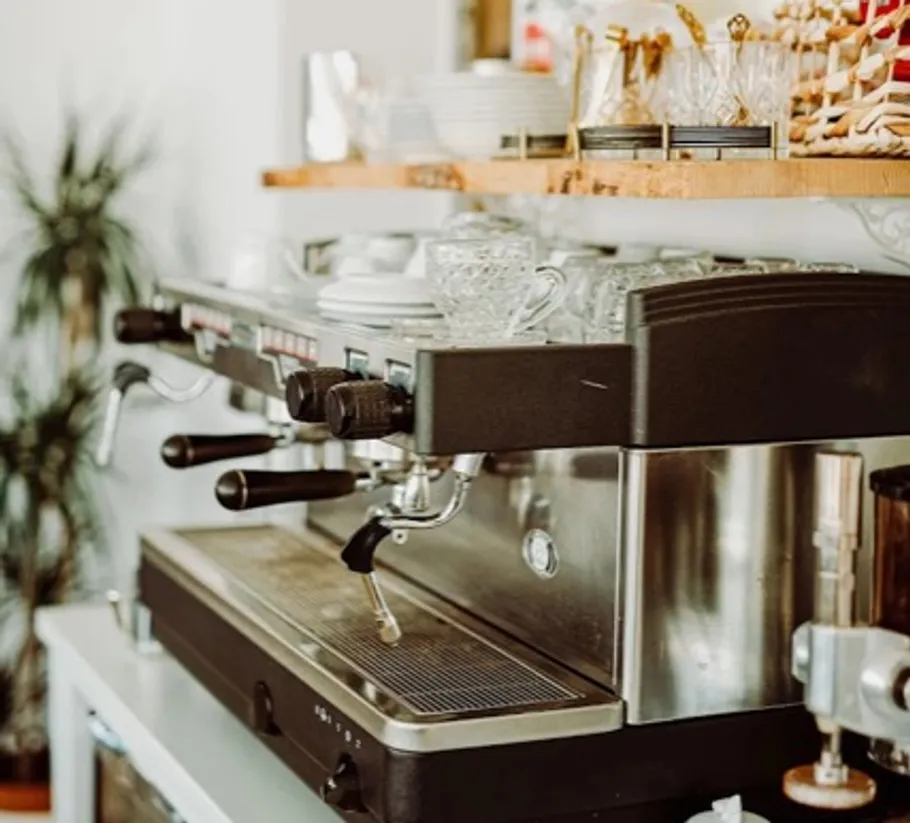 Espresso machine on counter with glassware.