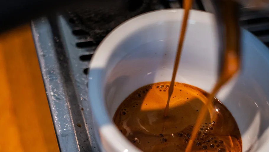 Kaffee wird in weiße Tasse, Metallmaschine gegossen.
