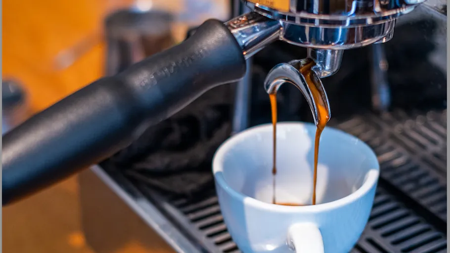 Espressomaschine gießt Kaffee in Tasse.