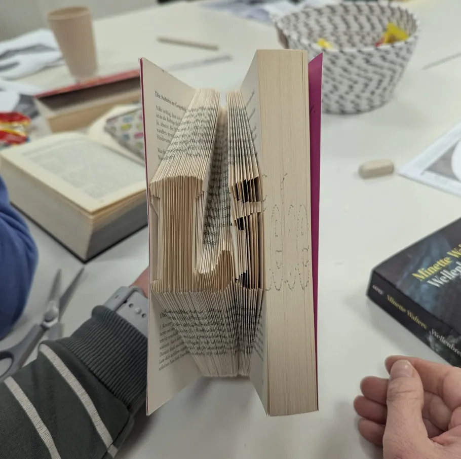 Book with folded pages spelling 'Life' on table.