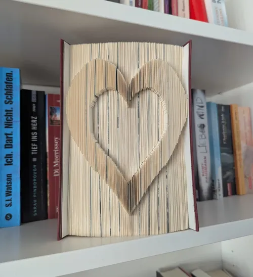 Buch mit Herzform gefalteten Seiten im Regal.