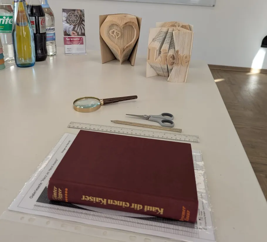 Crafted books with heart and tools on table.