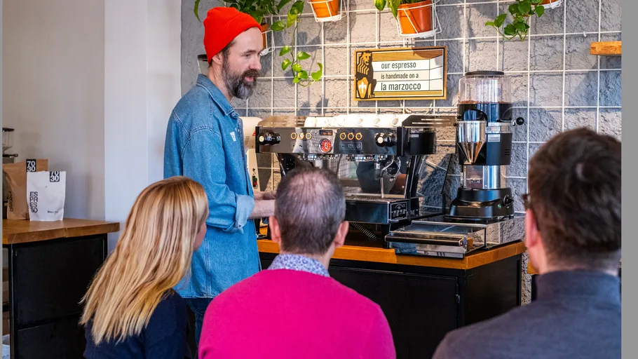 Barista demonstriert Espressomaschine für Kunden.