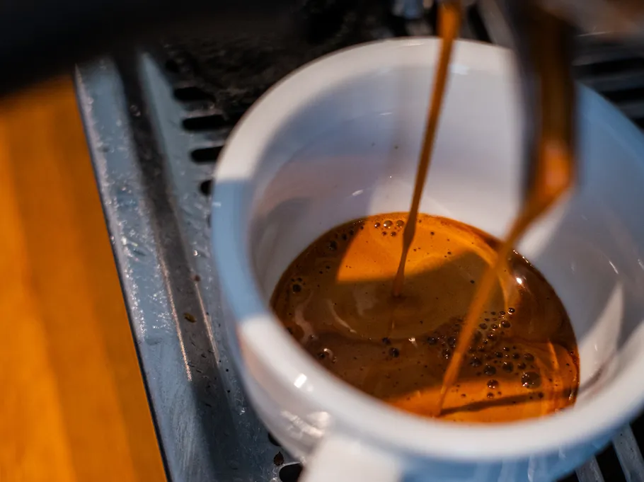 Espresso fließt in eine weiße Tasse.