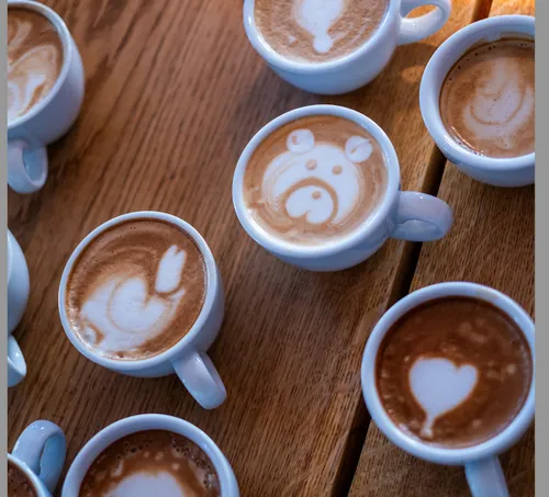 Tassen Latte mit Kunst auf Holztisch.