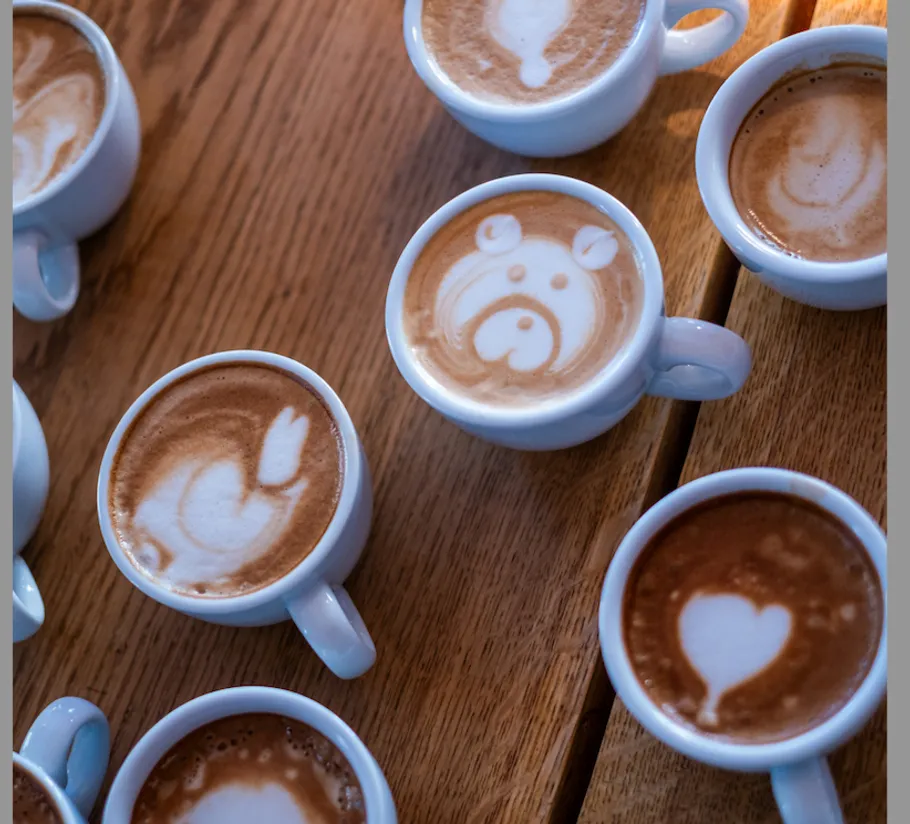 Tassen Latte mit Kunst auf Holztisch.
