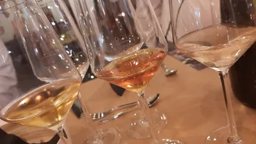 Three wine glasses on wooden table.