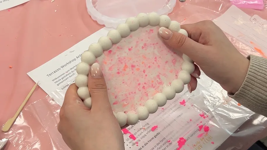 Hands holding a round object during crafting.