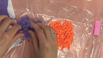 Hands sorting purple and orange fragments.