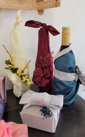 Flaschen in buntem Stoff auf Tisch verpackt.