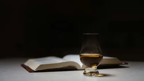 Whiskey glass in front of open book.