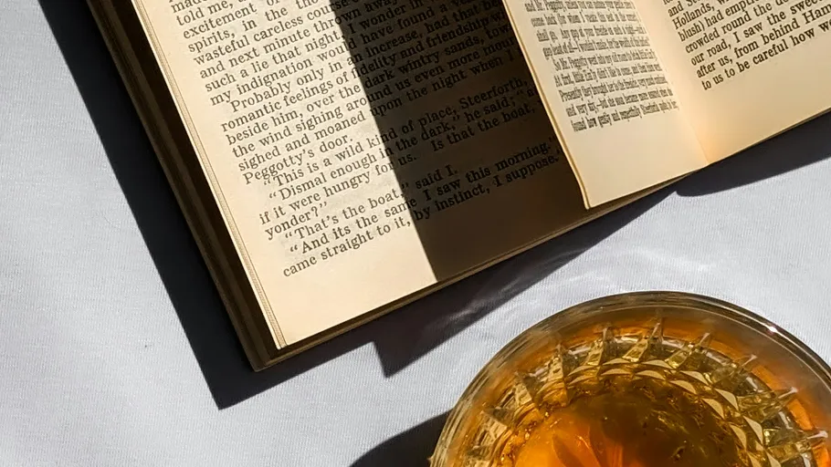 Open book with drink on table.