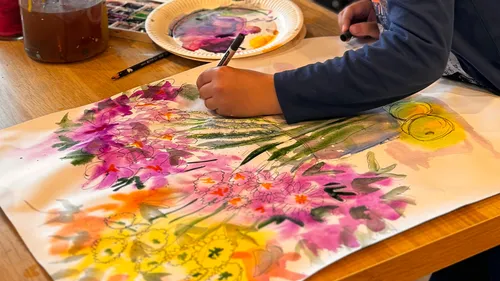 Kind malt bunte Blumen auf Papier.