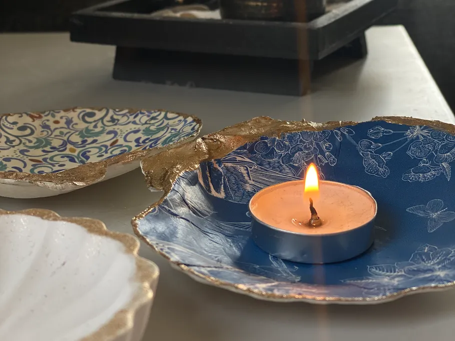 Kerze brennt auf blauem Dekoteller.