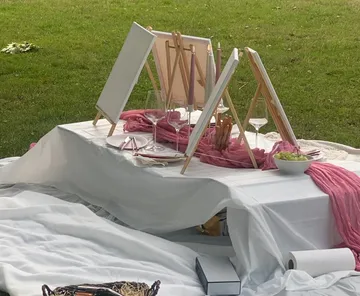 Picknick-Setup mit Staffeleien auf Grasfeld.