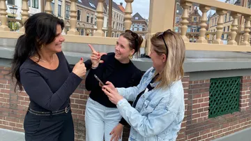 Three women conversing happily outdoors in city.