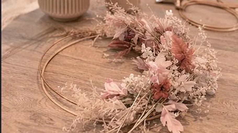 Flower wreath resting on wooden table.