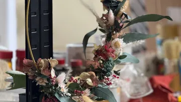 Getrockneter Blumenkranz auf schwarzem Metallständer.