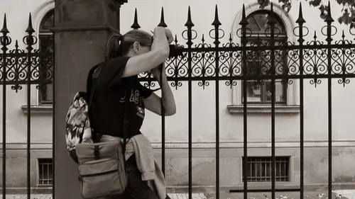 Person leaning on iron fence, urban background.