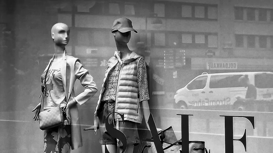 Zwei Schaufensterpuppen in einem Schaufenster mit Verkauf.