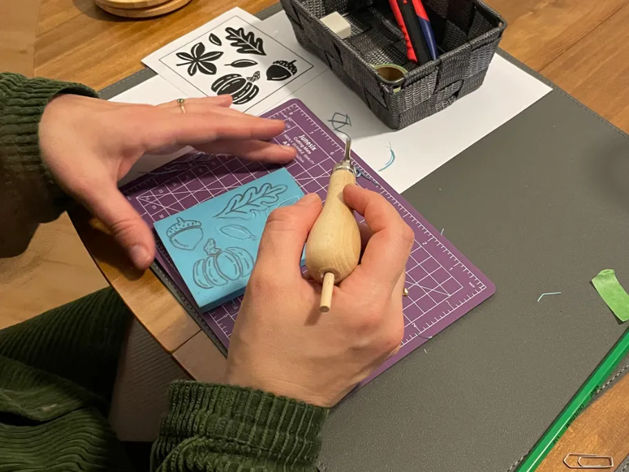 Hände schnitzen blaues Gummi mit Werkzeug und Mustern.