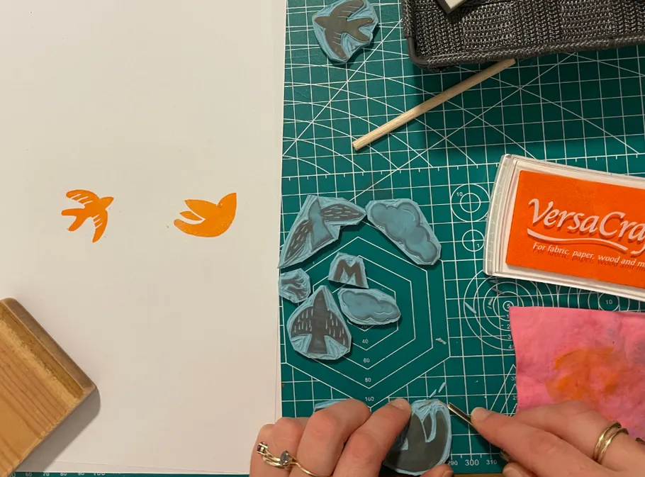 Bird stamps being carved and stamped on paper.