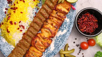 Mixed kebabs with rice on decorated plate.