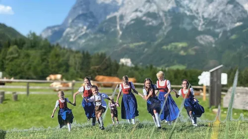Kinder in Tracht rennen in den Bergen.