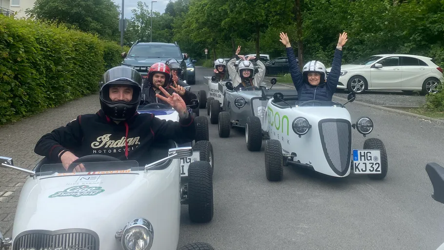 People in mini cars on a street.
