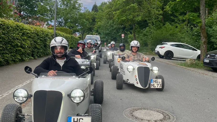 People driving small vintage cars on street.