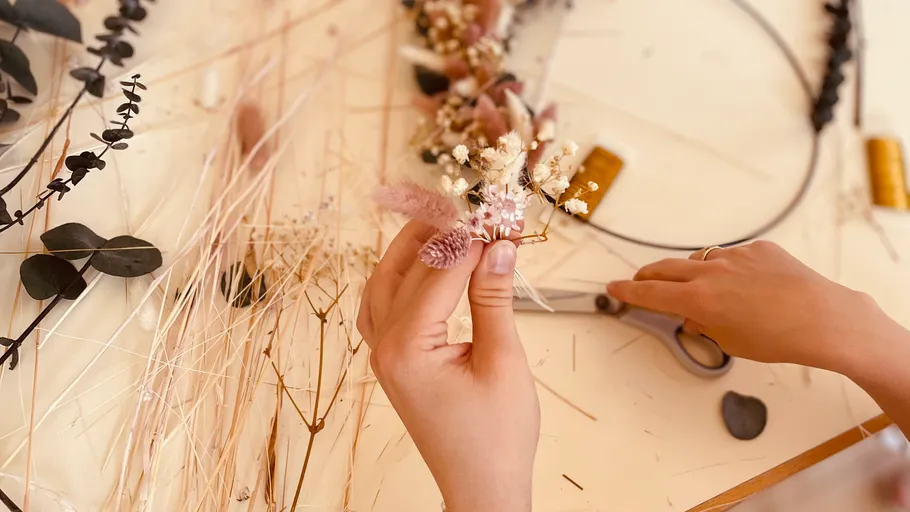 Hands arranging dried flowers on a table.
